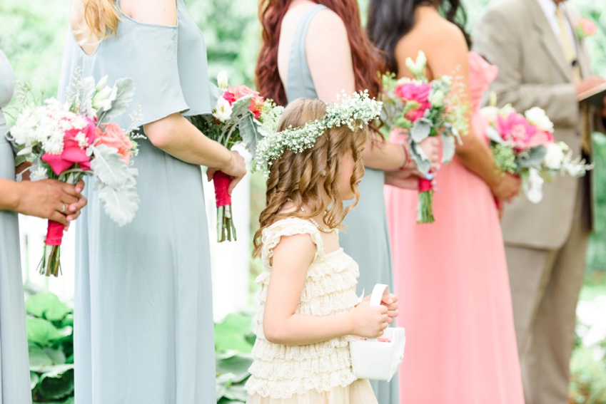 flower girl and bridesmaids standing during outdoor garden ceremony