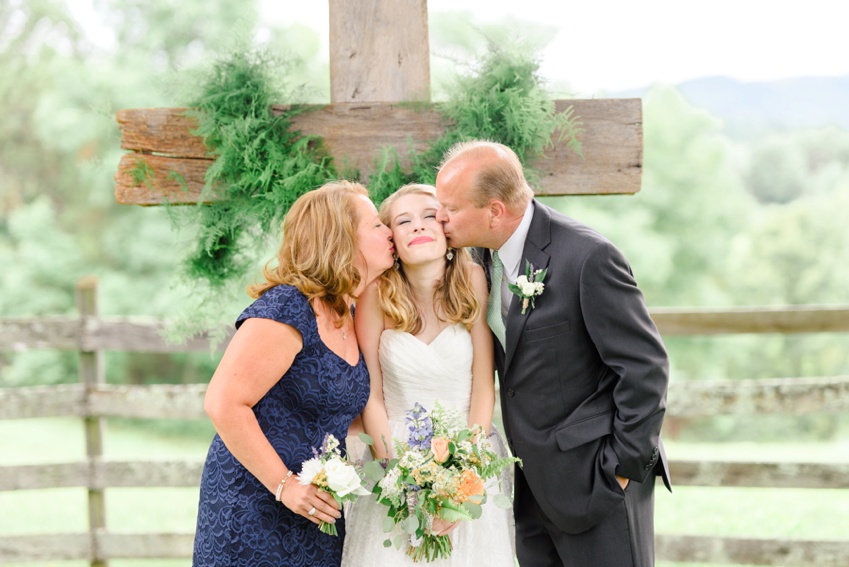 parents kissing bride on her wedding day