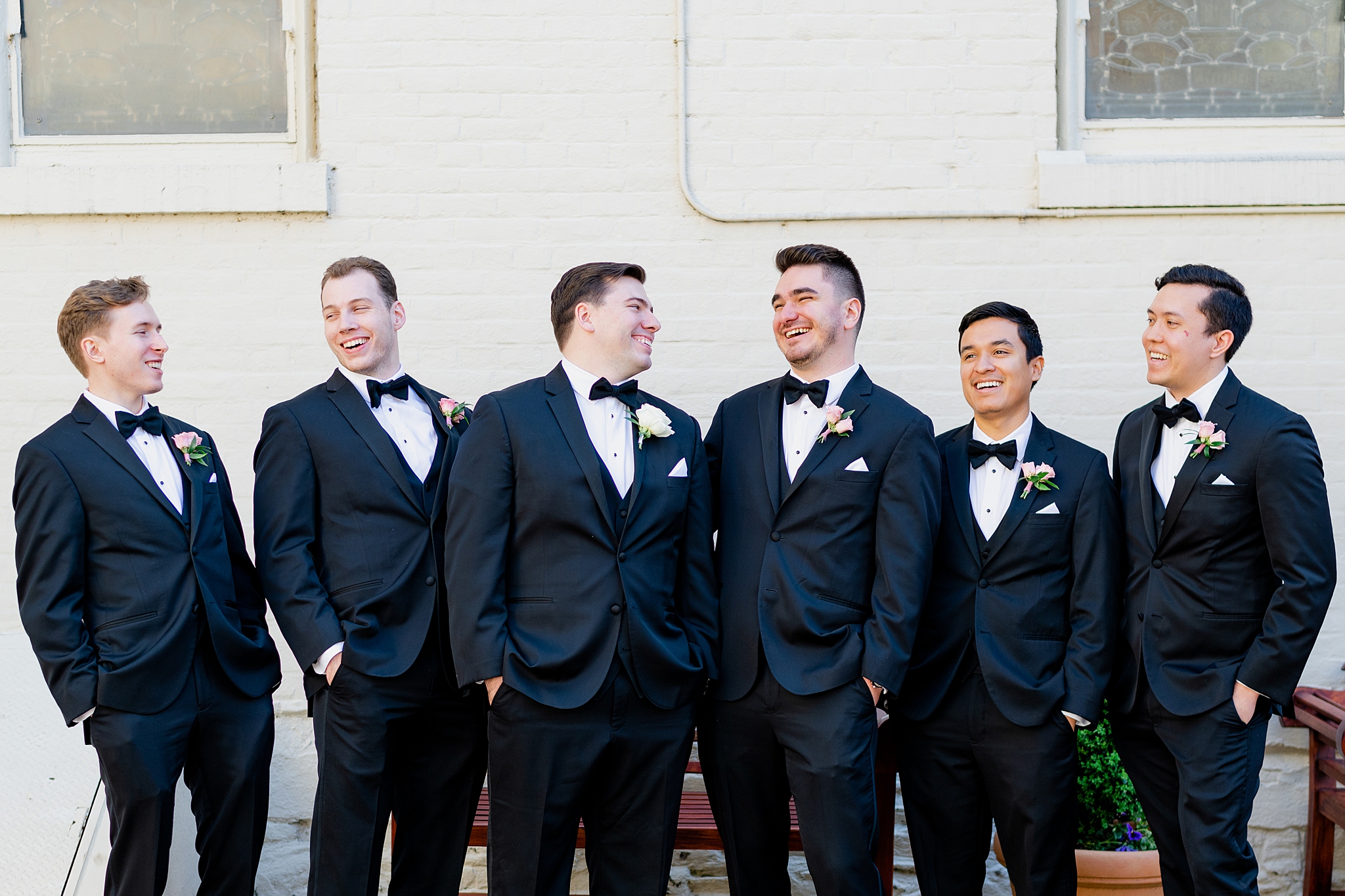 Groom and groomsmen looking at each other and laughing.