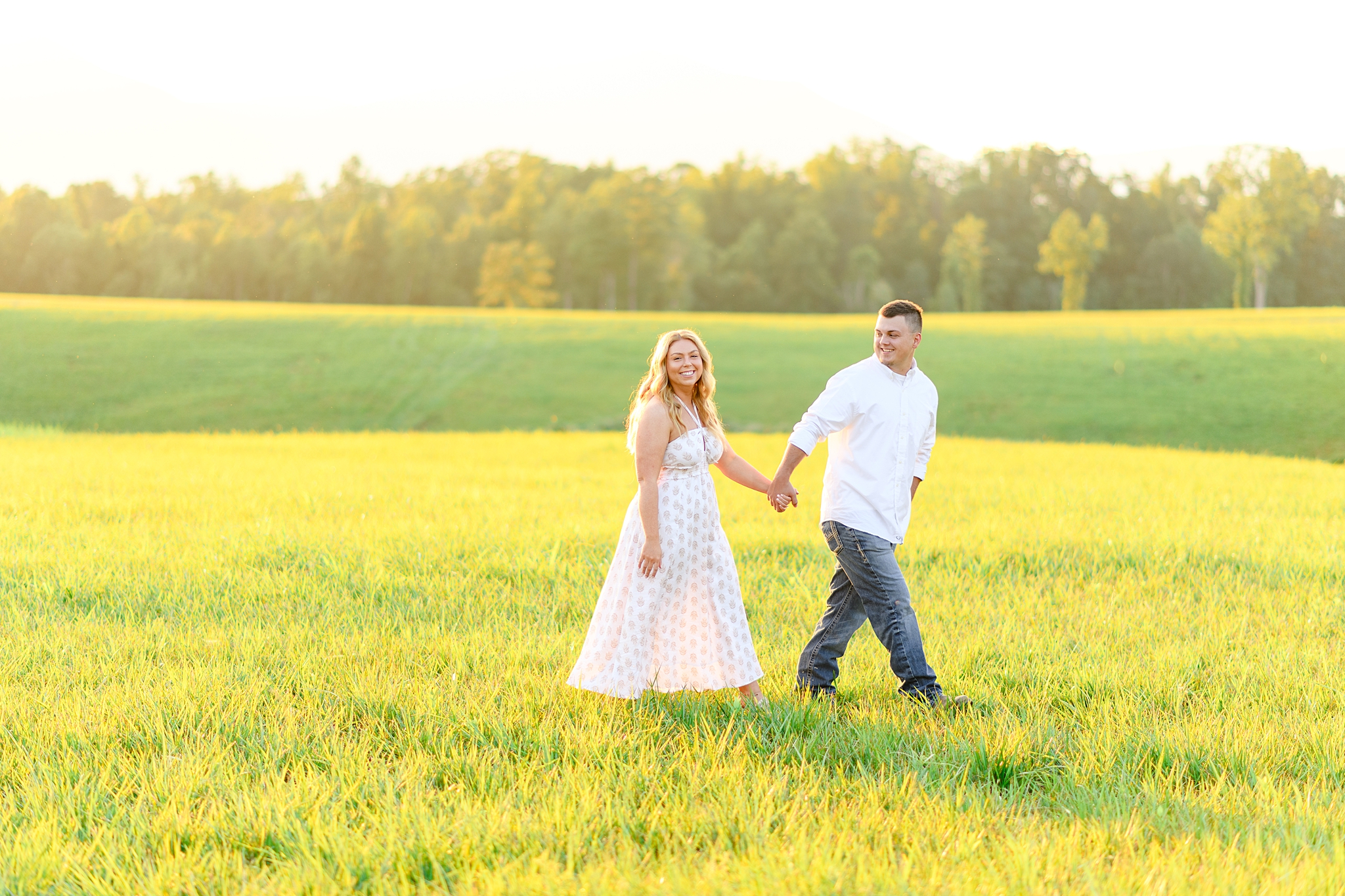 newlyweds walking in the field at sunset