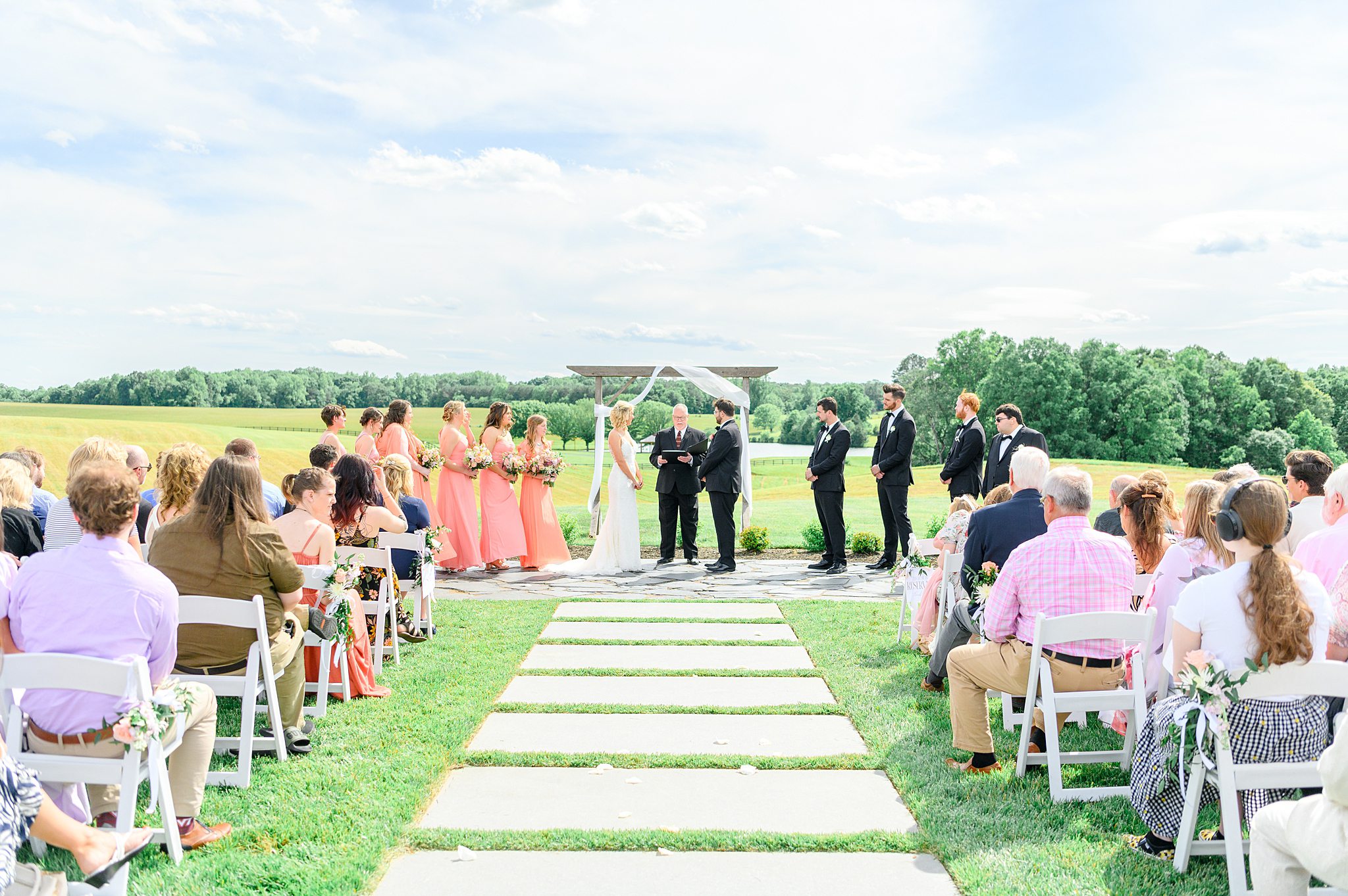 Outdoor Spring Grove wedding ceremony setup with white chairs and tulle arch