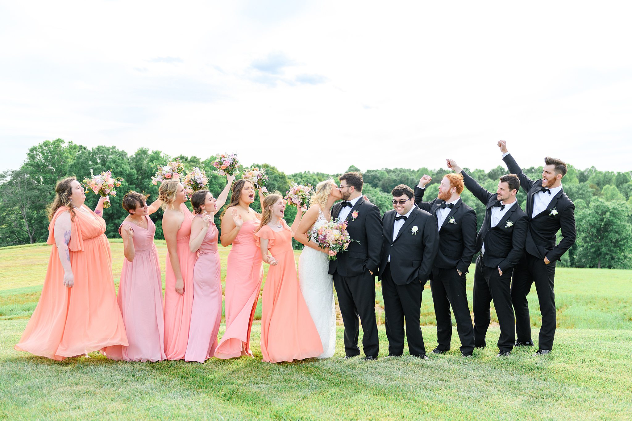 bridal party cheering while newlyweds are kissing