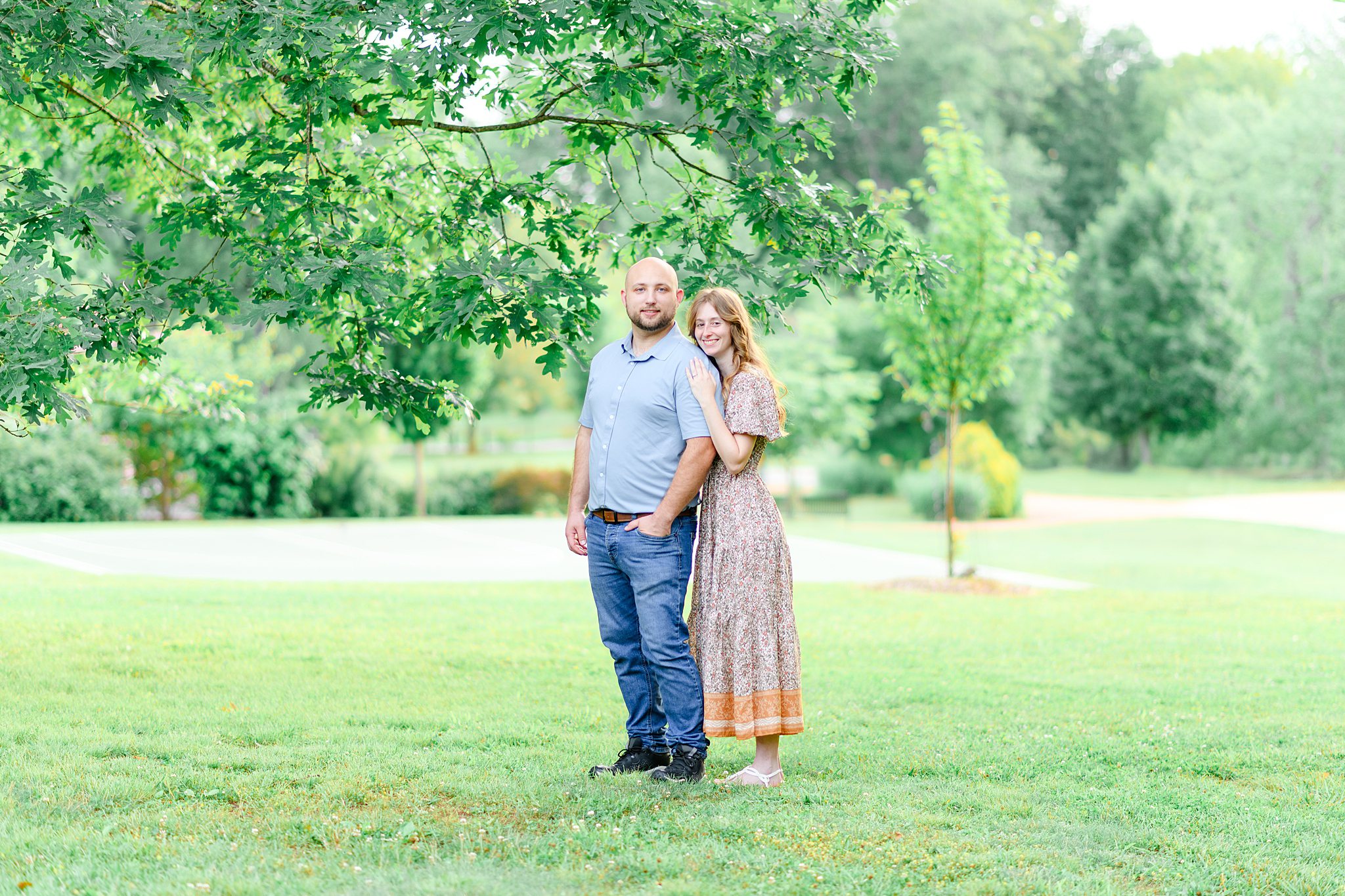 Bride-to-be leaning on fiance at Riverside PArk