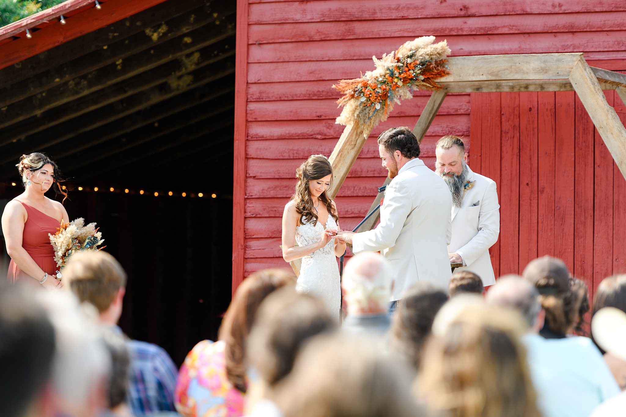 Bride and groom holding hands and exchanging vows under the wooden arbor
