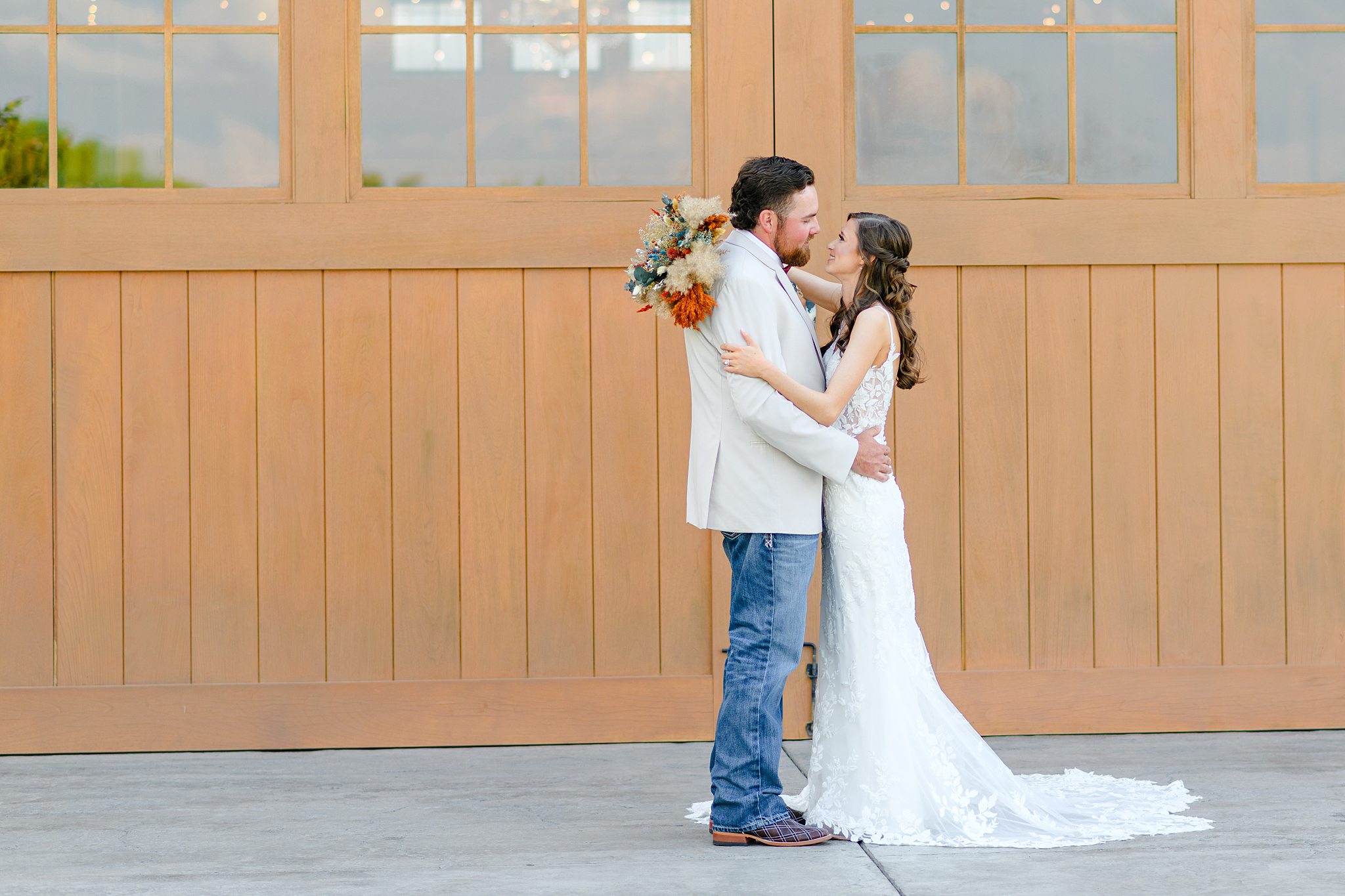 Bride and groom standing in front reception barn