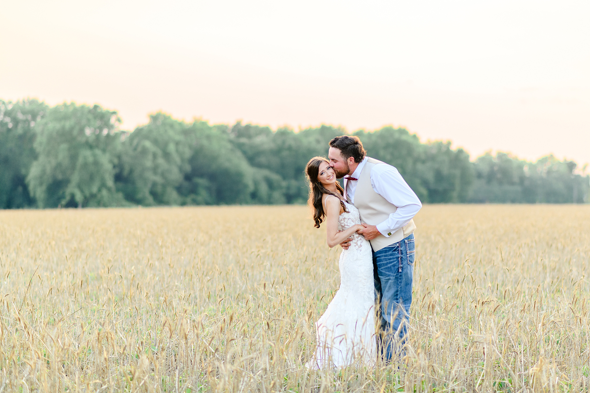 Romantic portrait of bride and groom in front of a field