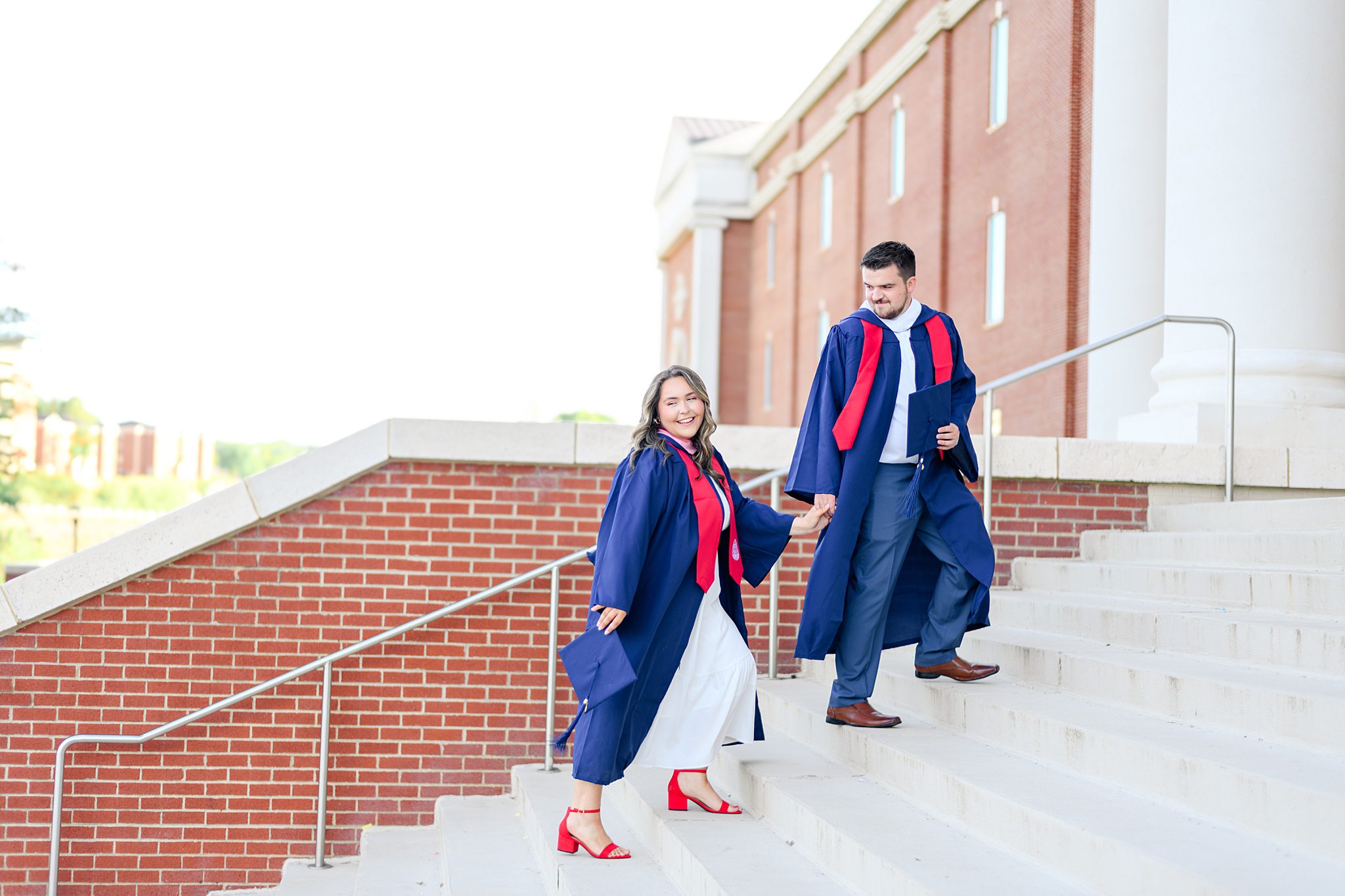 couple walking at liberty university in cap and gown